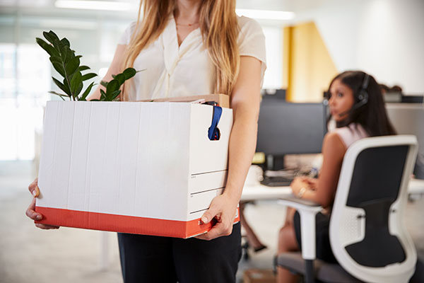 Employee leaving office with cardboard box of belongings.