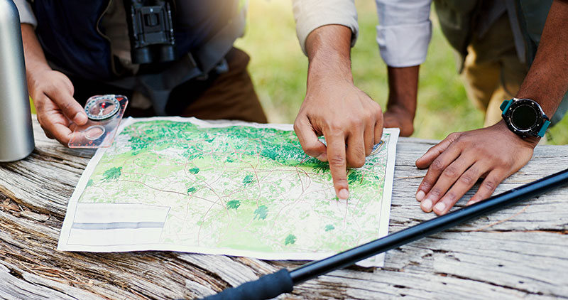 two people looking over a map with a compass in the woods.