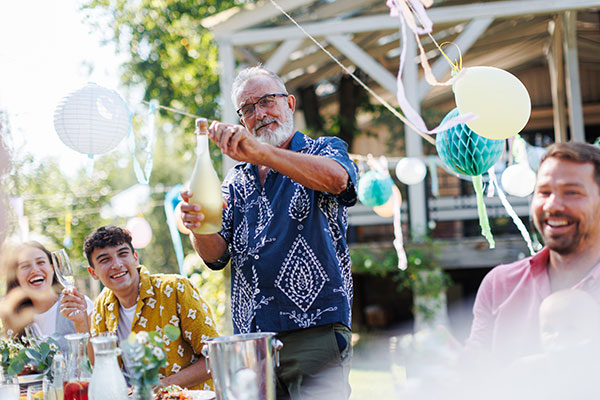 Retirement party with a grandfather opening a bottle of champagne.